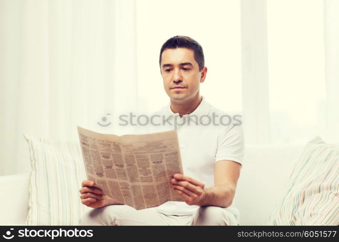 leisure, information, people and mass media concept - man reading newspaper at home