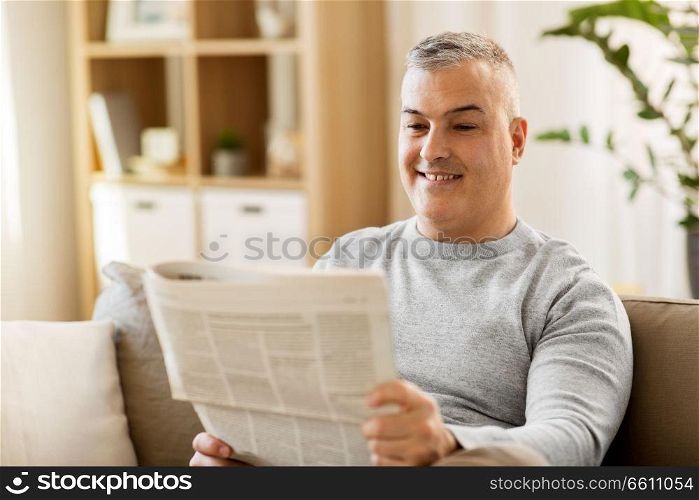 leisure, information, people and mass media concept - man reading newspaper at home. man reading newspaper at home