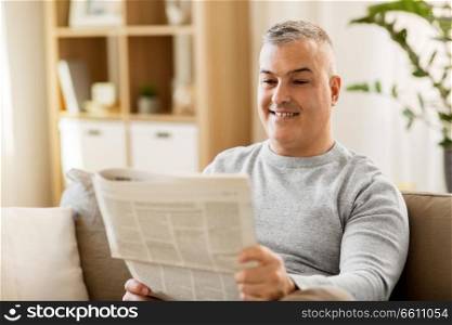 leisure, information, people and mass media concept - man reading newspaper at home. man reading newspaper at home