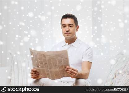 leisure, information, people and mass media concept - man reading newspaper at home over snow effect