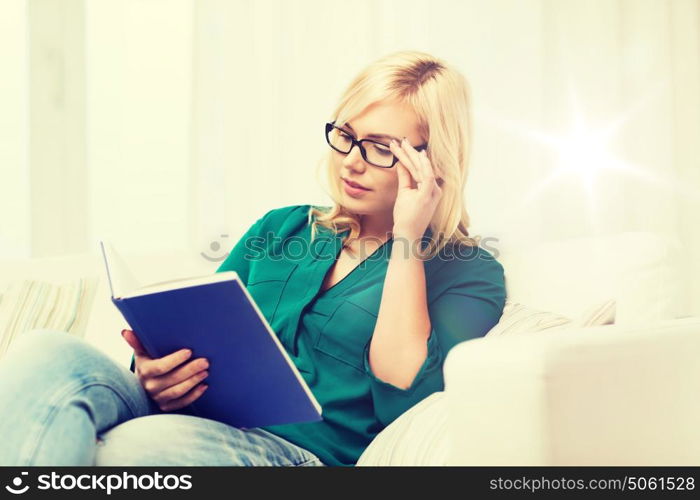 leisure, literature, education and people concept - young woman in glasses reading book at home. young woman in glasses reading book at home