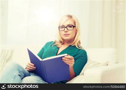 leisure, literature, education and people concept - young woman in glasses reading book at home. young woman in glasses reading book at home. young woman in glasses reading book at home