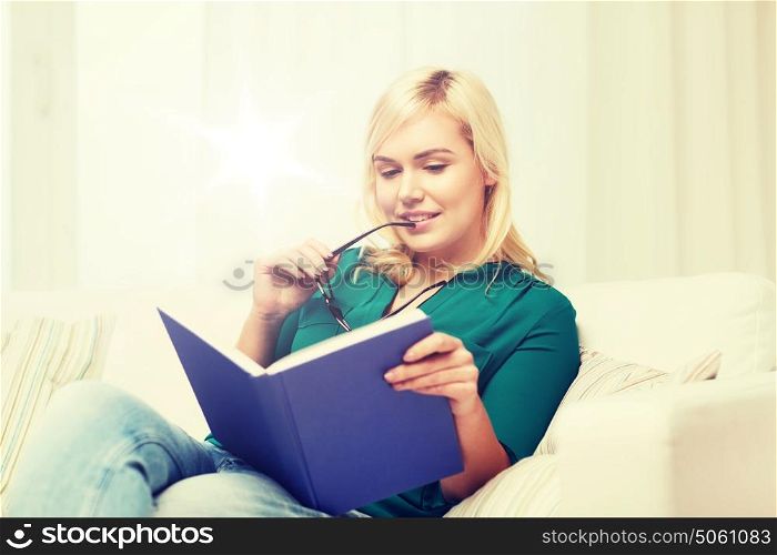 leisure, literature, education and people concept - young woman with glasses reading book at home. young woman with glasses reading book at home