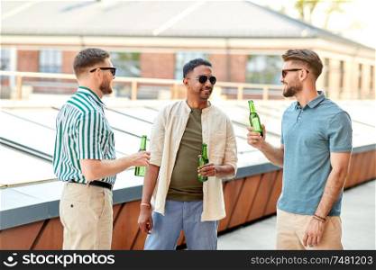 leisure, male friendship and people concept - happy men or friends drinking beer and talking at rooftop party in summer. happy male friends drinking beer at rooftop party