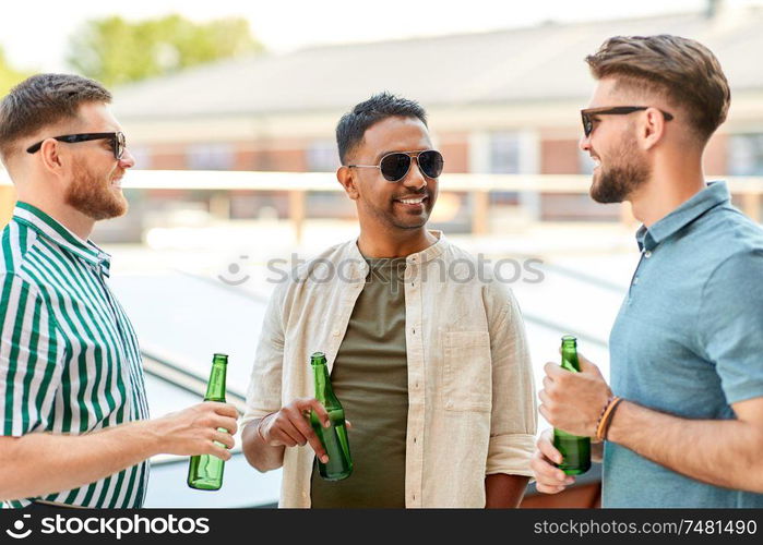 leisure, male friendship and people concept - happy men or friends drinking beer and talking at rooftop party in summer. happy male friends drinking beer at rooftop party