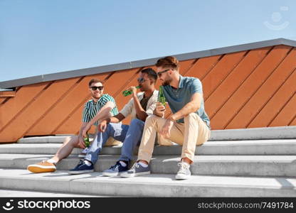 leisure, male friendship and people concept - happy men or friends drinking beer and talking on street in summer. happy male friends drinking beer on street