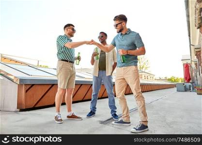 leisure, male friendship and people concept - happy men or friends meeting and drinking beer at rooftop party in summer. happy male friends with beer meeting on rooftop