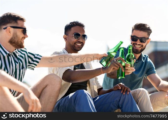 leisure, male friendship and people concept - happy men or friends toasting and drinking beer on street in summer. happy male friends drinking beer on street