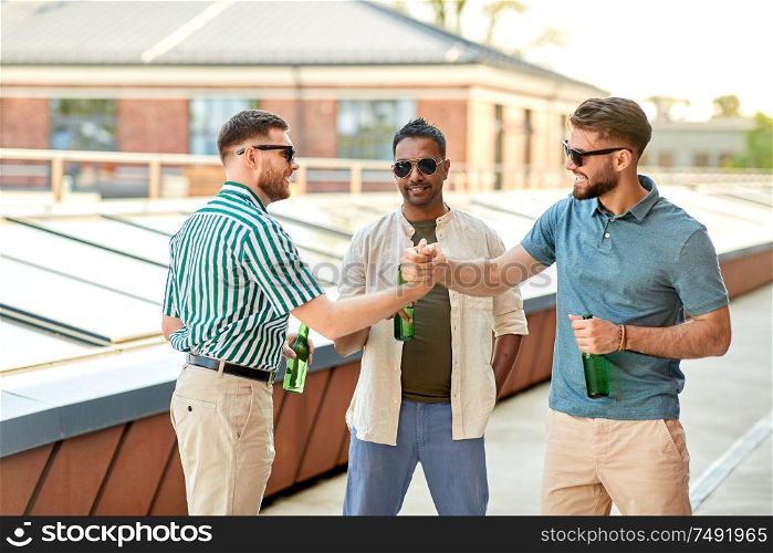 leisure, male friendship and people concept - happy men or friends with beer meeting at rooftop party in summer. happy male friends drinking beer at rooftop party