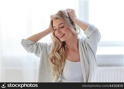 leisure, morning and people concept - happy young woman stretching at home