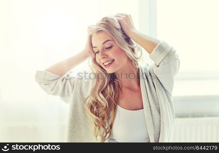 leisure, morning and people concept - happy young woman stretching at home. happy young woman stretching at home