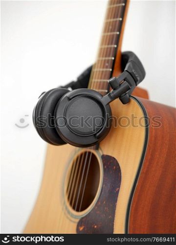 leisure, music and musical instruments concept - close up of acoustic guitar and headphones. close up of acoustic guitar and headphones
