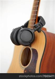leisure, music and musical instruments concept - close up of acoustic guitar and headphones. close up of acoustic guitar and headphones