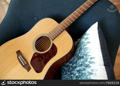 leisure, music and musical instruments concept - close up of acoustic guitar on armchair. close up of acoustic guitar on armchair