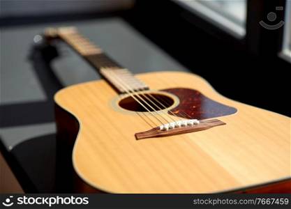leisure, music and musical instruments concept - close up of acoustic guitar on window sill. close up of acoustic guitar on window sill