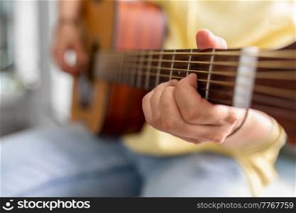 leisure, music and people concept - close up of man playing guitar sitting on windowsill. close up of man playing guitar sitting on sill