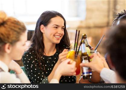 leisure, party and people concept - happy friends clinking drinks at bar. happy friends clinking drinks at bar