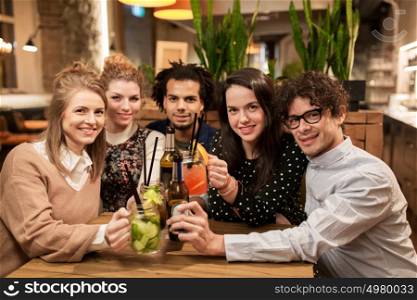 leisure, party, people and holidays concept - happy friends clinking drinks at bar or cafe. happy friends with drinks at bar or cafe