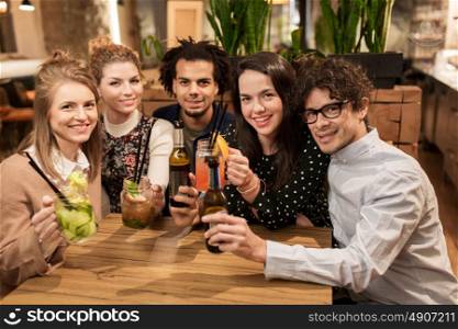 leisure, party, people and holidays concept - happy friends with drinks at bar or cafe. happy friends with drinks at bar or cafe