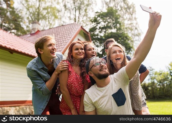 leisure, party, technology, people and holidays concept - happy friends taking selfie with smartphone at summer garden
