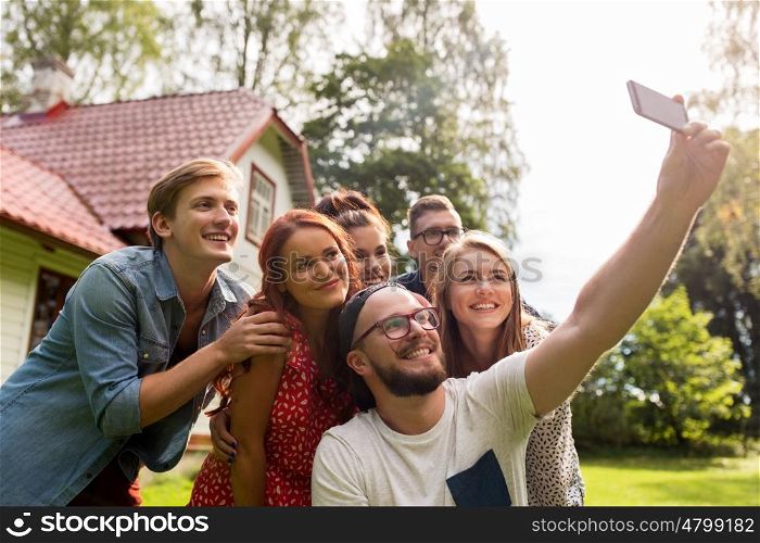 leisure, party, technology, people and holidays concept - happy friends taking selfie with smartphone at summer garden