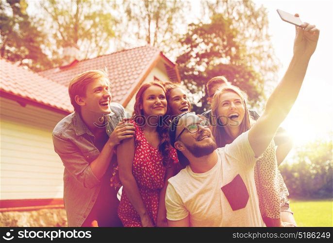 leisure, party, technology, people and holidays concept - happy friends taking selfie with smartphone at summer garden. friends taking selfie at party in summer garden