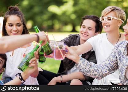 leisure, people and celebration concept - happy friends clinking non alcoholic drinks at summer park. happy friends clinking drinks at summer park