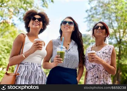 leisure, people and friendship concept - happy women or friends with takeaway drinks summer park. happy women or friends with drinks at summer park