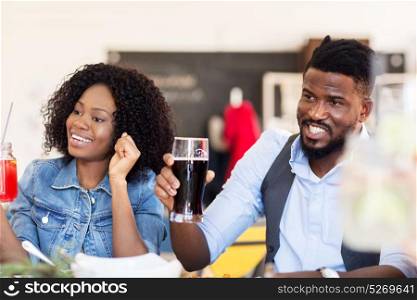 leisure, people and holidays concept - happy african american couple with drinks at bar or restaurant. happy african american couple with drinks at bar