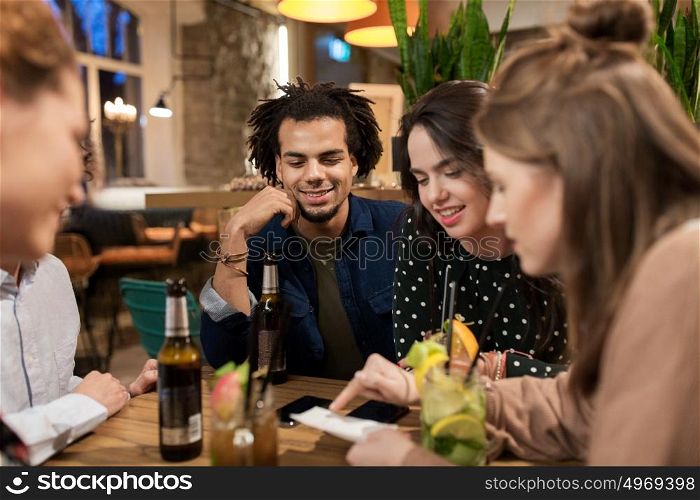 leisure, people and holidays concept - happy friends with drinks and bill at bar or cafe. happy friends with drinks and bill at bar or cafe