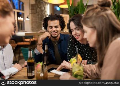 leisure, people and holidays concept - happy friends with drinks and bill at bar or cafe. happy friends with drinks and bill at bar or cafe
