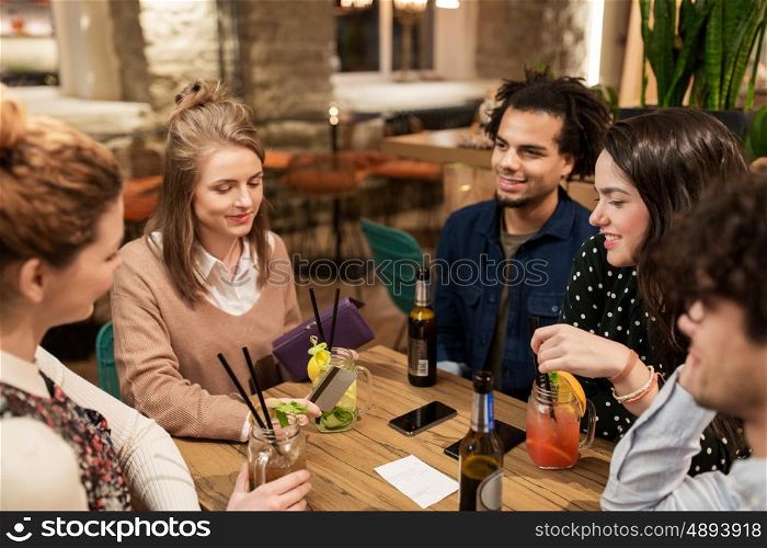 leisure, people and holidays concept - happy friends with drinks, credit card and bill at bar or cafe