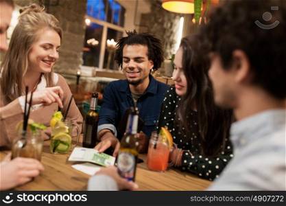 leisure, people and holidays concept - happy friends with drinks, money and bill at bar or cafe. friends with drinks, money and bill at bar
