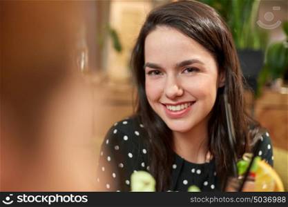 leisure, people and holidays concept - happy smiling young woman with drink at bar or cafe. happy smiling young woman with drink at bar