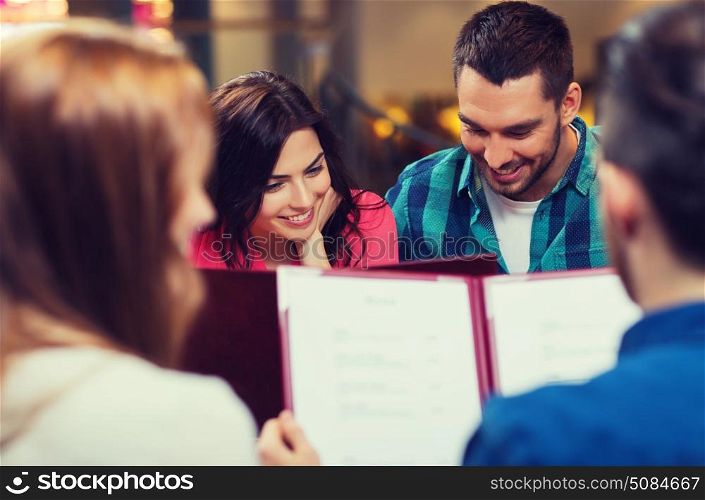 leisure, people and holidays concept - smiling couple with friends reading menu at restaurant. smiling couple with friends and menu at restaurant. smiling couple with friends and menu at restaurant
