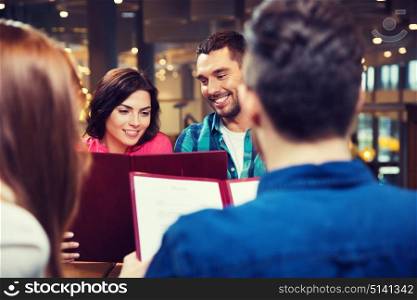 leisure, people and holidays concept - smiling couple with friends reading menu at restaurant. smiling couple with friends and menu at restaurant