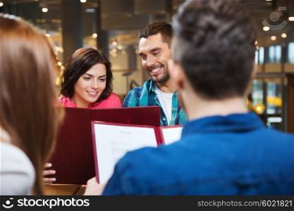 leisure, people and holidays concept - smiling couple with friends reading menu at restaurant