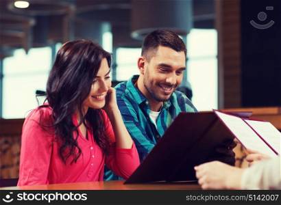 leisure, people and holidays concept - smiling couple with menus at restaurant. smiling couple with menus at restaurant