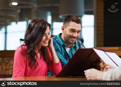 leisure, people and holidays concept - smiling couple with menus at restaurant