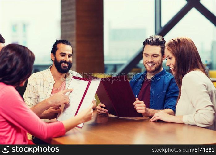 leisure, people and holidays concept - smiling friends discussing menu at restaurant. smiling friends discussing menu at restaurant