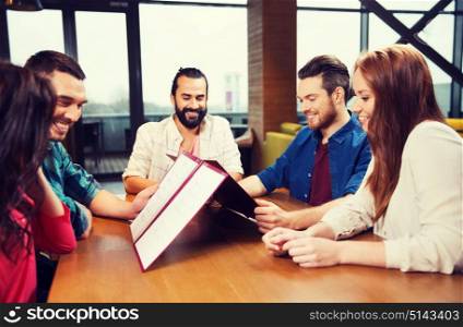 leisure, people and holidays concept - smiling friends discussing menu at restaurant. smiling friends discussing menu at restaurant