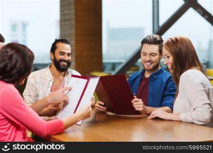 leisure, people and holidays concept - smiling friends discussing menu at restaurant