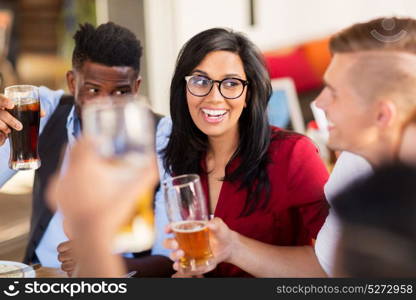 leisure, people and holidays concept - smiling friends having dinner and drinking beer at restaurant or pub. friends dining and drinking beer at restaurant