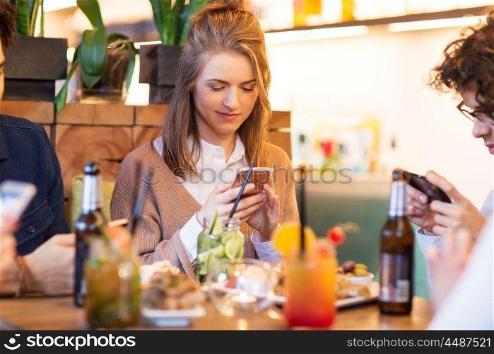 leisure, people and technology concept - happy friends with smartphones eating and drinking at restaurant. friends with smartphones eating at restaurant. friends with smartphones eating at restaurant