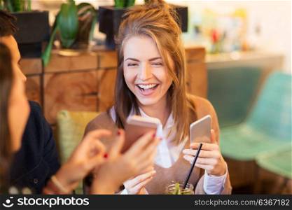 leisure, people and technology concept - happy woman with smartphone and friends at restaurant. woman with smartphone and friends at restaurant