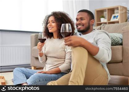 leisure, people and valentines day concept - happy african american couple drinking wine at home. african american couple drinking wine at home