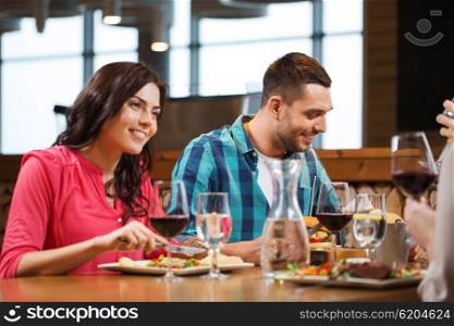 leisure, people, eating and holidays concept - happy couple with friends having dinner at restaurant