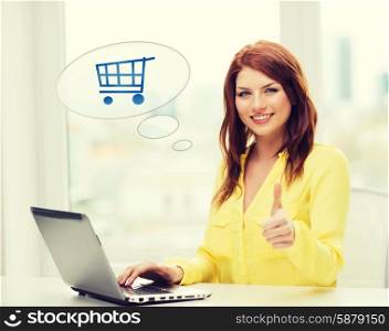 leisure, people, online shopping, gesture and technology concept - smiling young woman with laptop computer and trolley icon showing thumbs up at home
