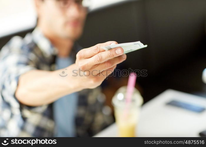 leisure, people, payment and finance concept - happy man with cash money paying at cafe