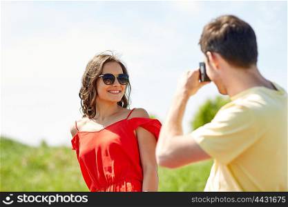 leisure, photography, summer holidays and people concept - happy couple with camera photographing outdoors